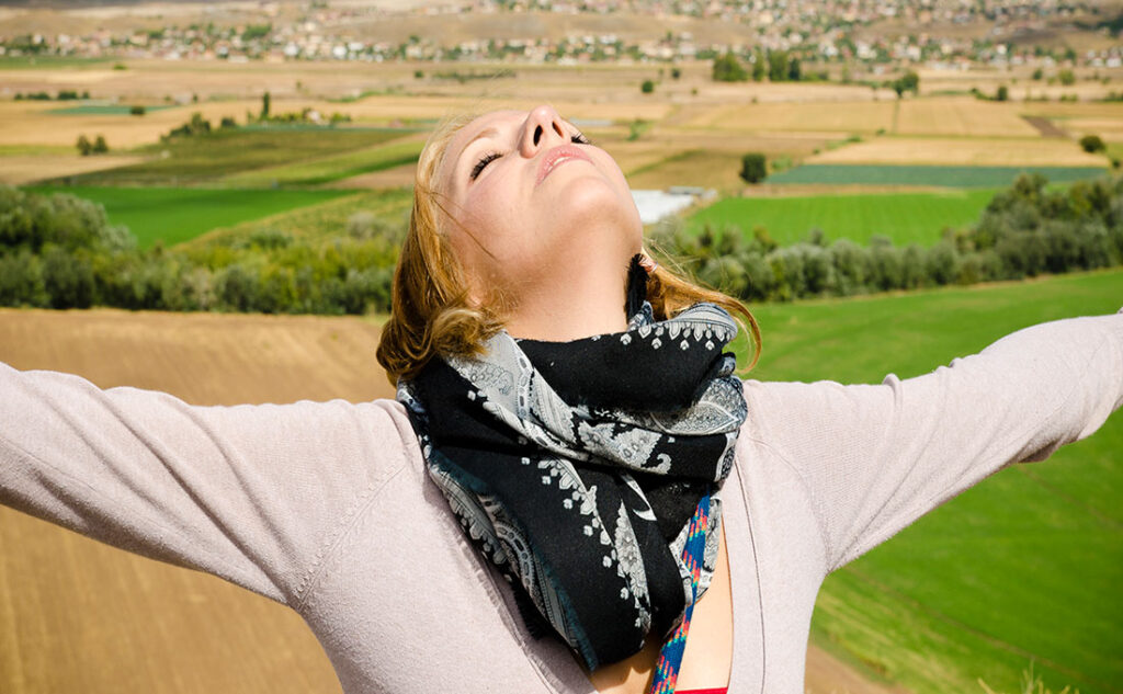 mujer respirando aire puro en un campo